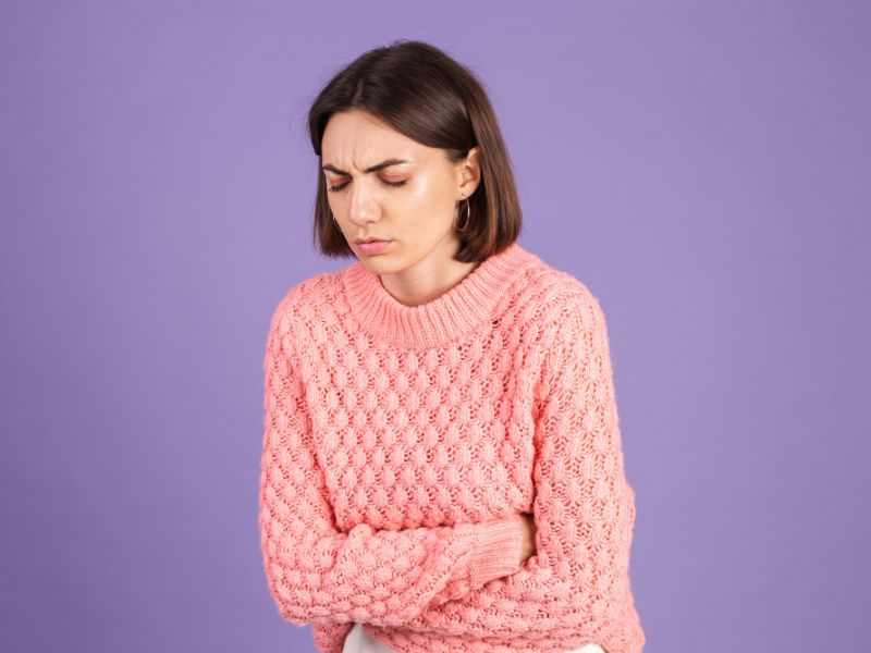 young brunette pink sweater isolated purple wall 1